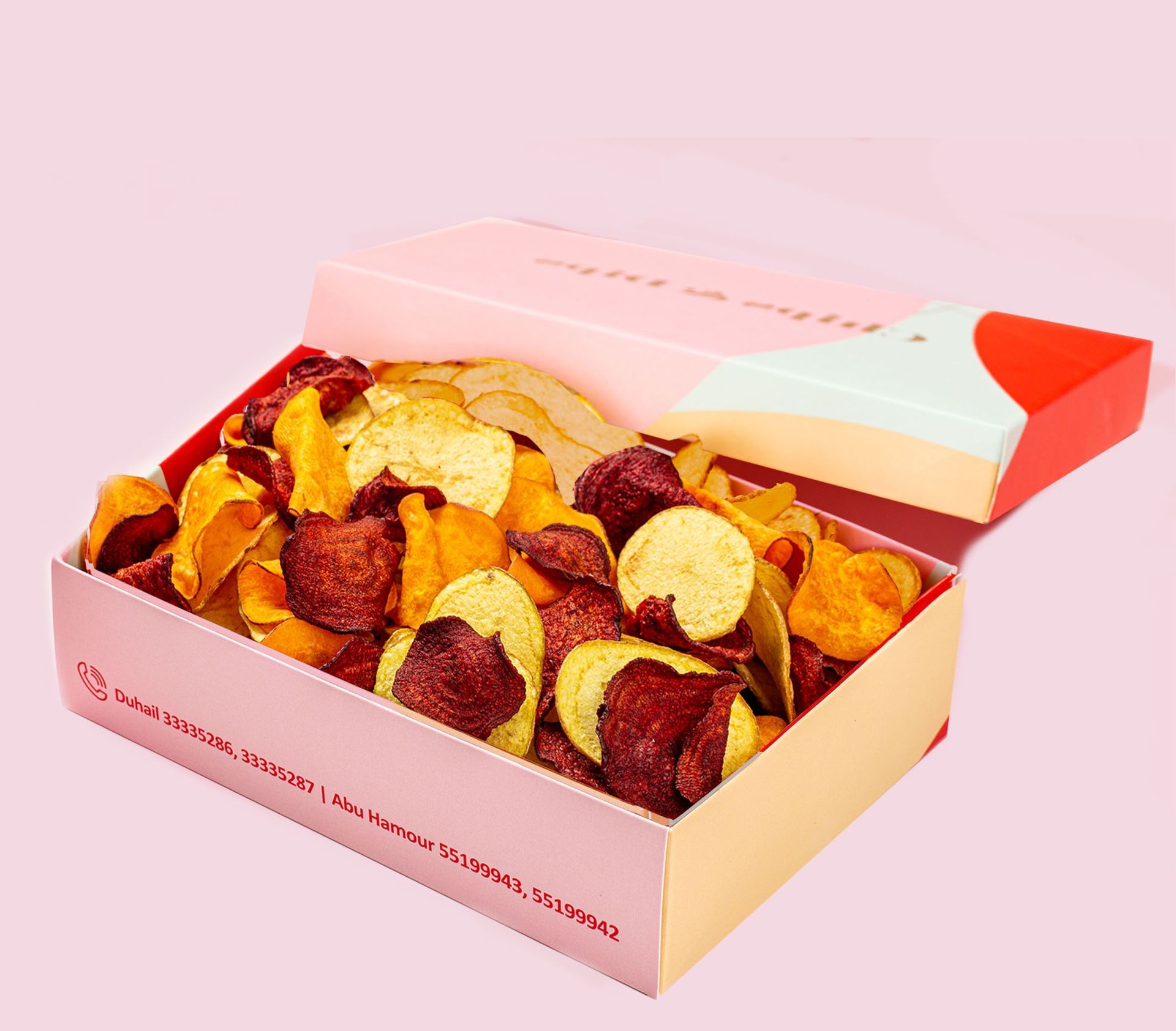 Box of assorted vegetable chips on a pink background.